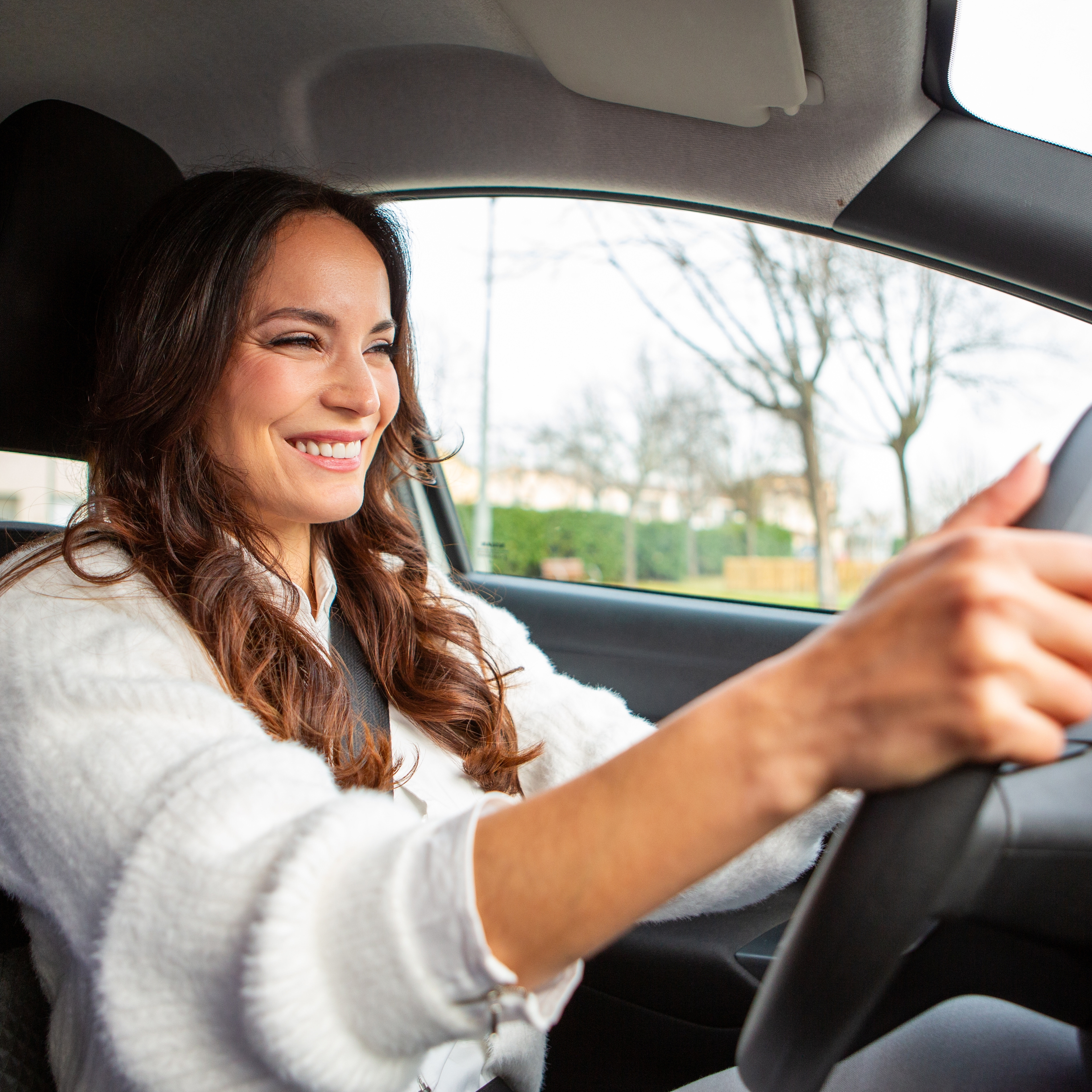 A happy woman driving in her car.