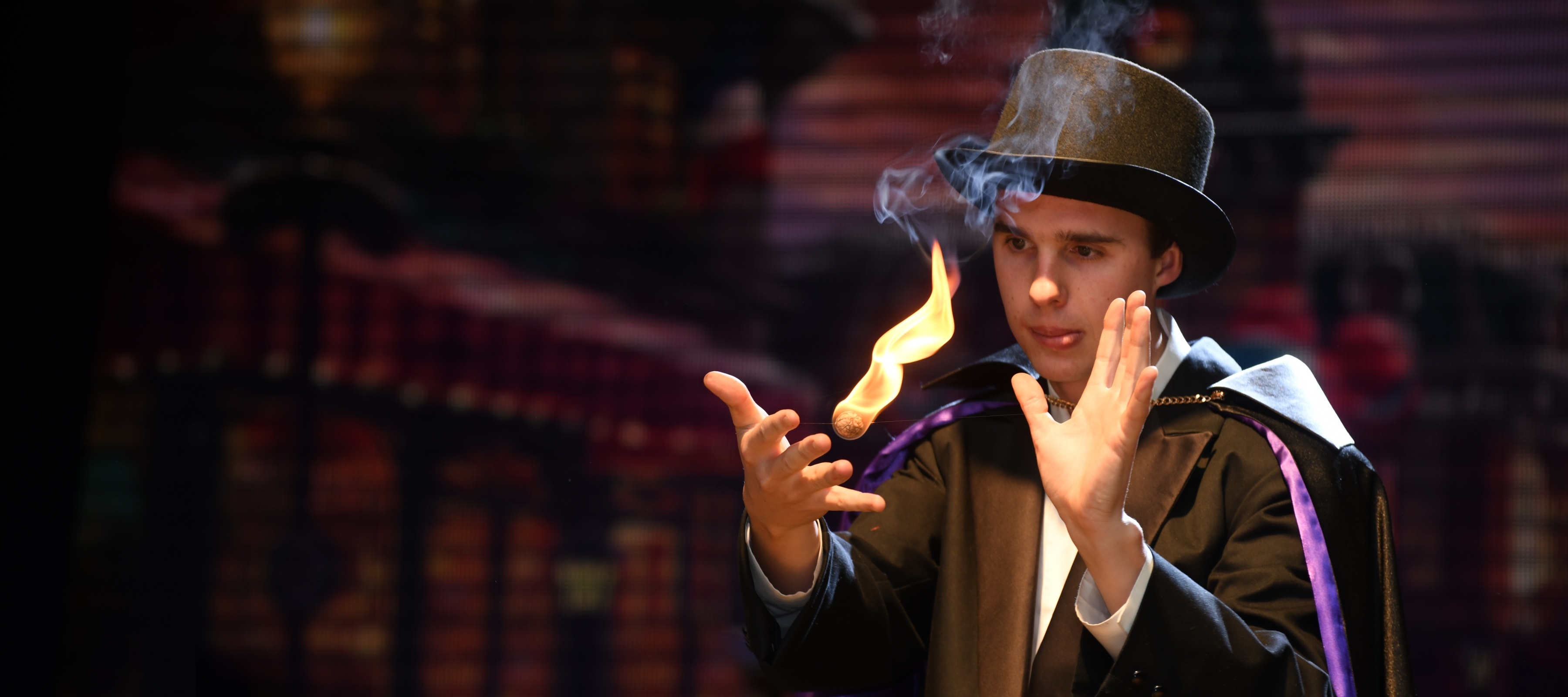 Magician manipulates a ball of flame for an illusion during a stage performance