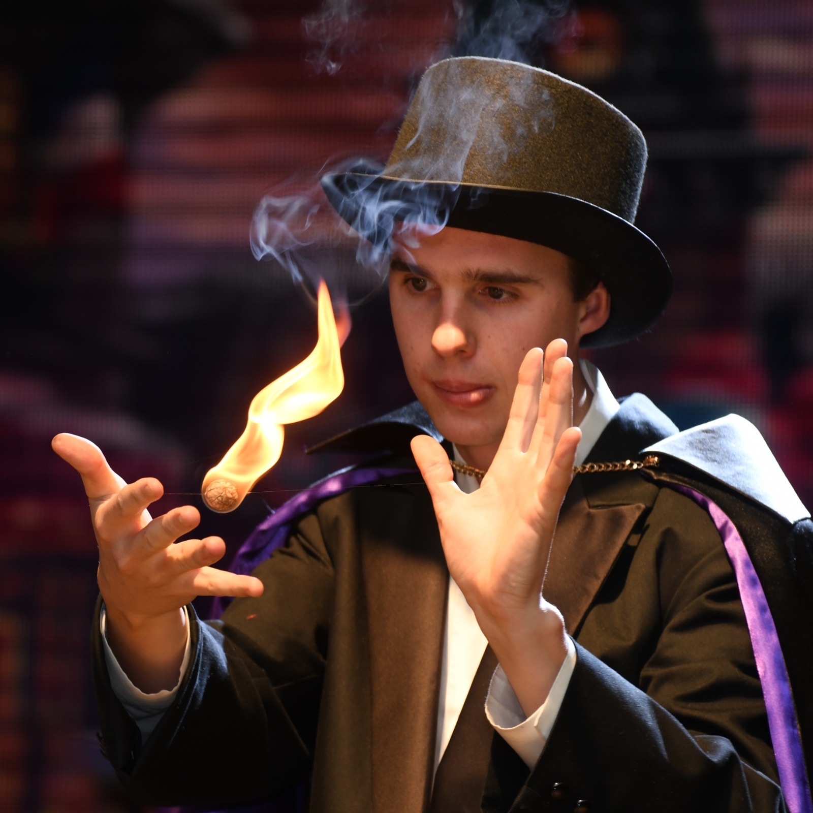 Magician manipulates a ball of flame for an illusion during a stage performance