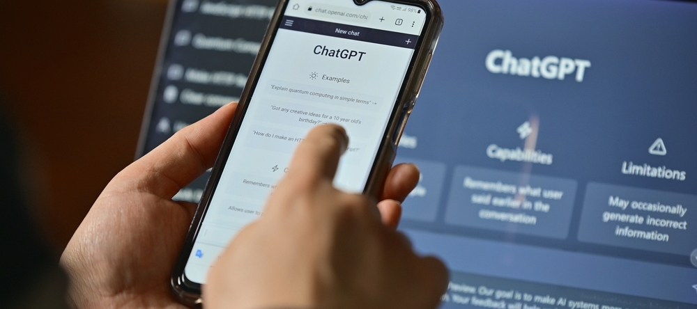 Computer screen with ChatGPT website and phone with mobile app on screen.