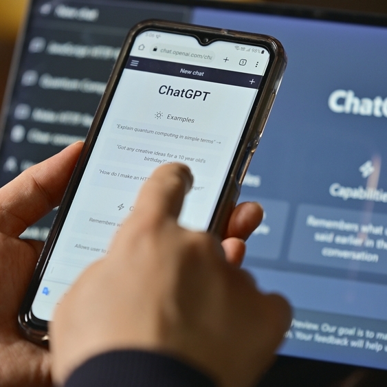 Computer screen with ChatGPT website and phone with mobile app on screen.