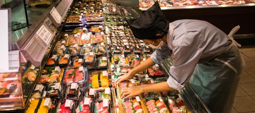 A photo of a grocery store working stocking sushi
