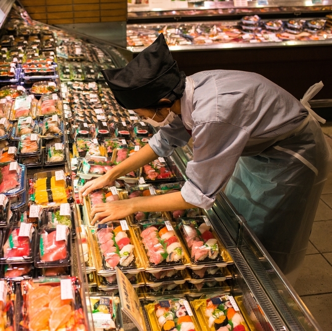 A photo of a grocery store working stocking sushi