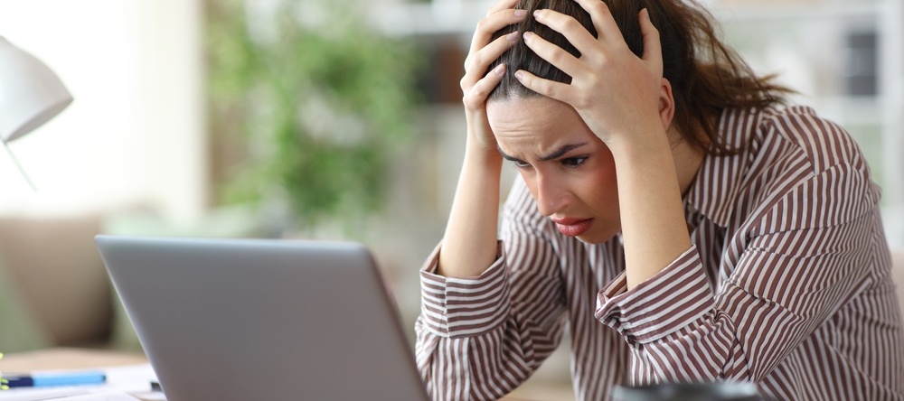A photo of a woman on her laptop stressed