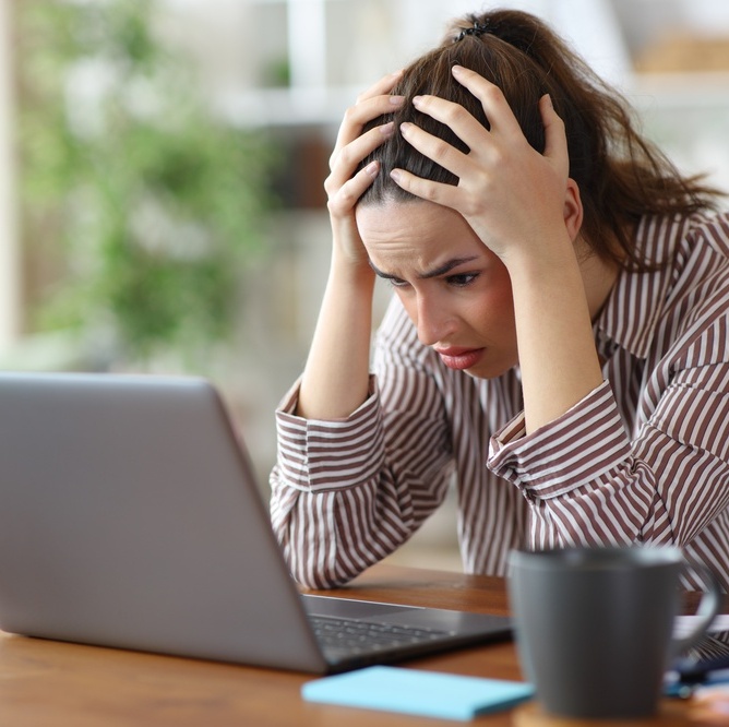A photo of a woman on her laptop stressed