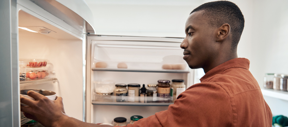 A photo of a man looking at leftovers in the fridge