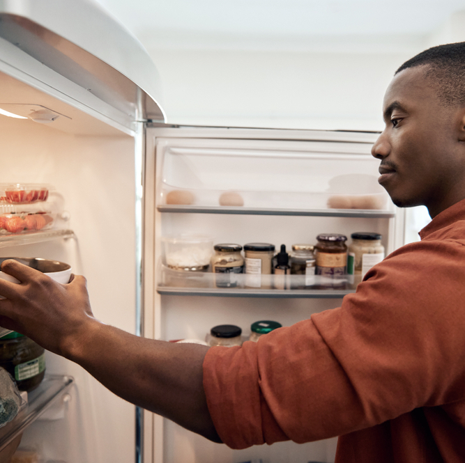 A photo of a man looking at leftovers in the fridge