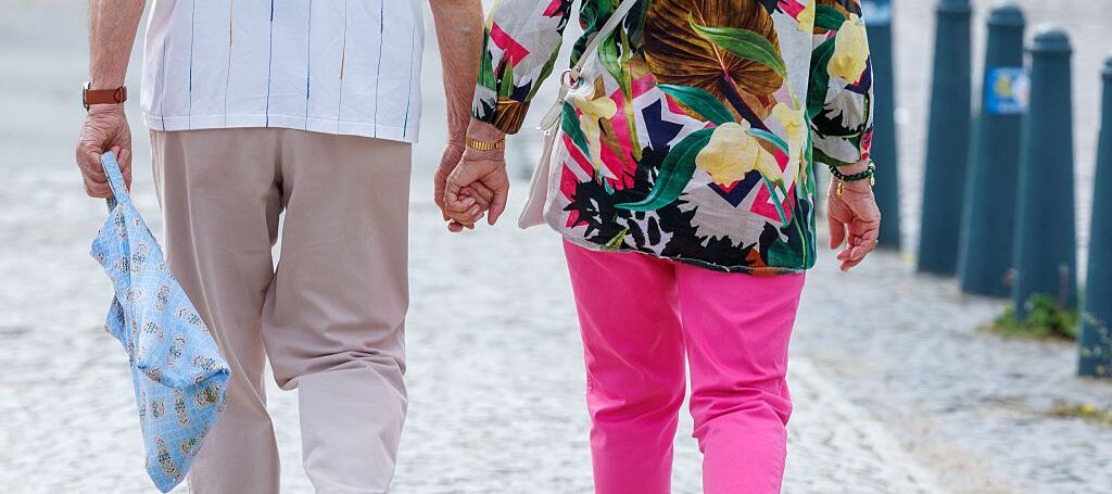 An elderly couple is taking a walk in the city center.