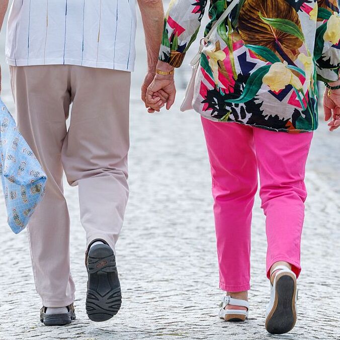 An elderly couple is taking a walk in the city center.