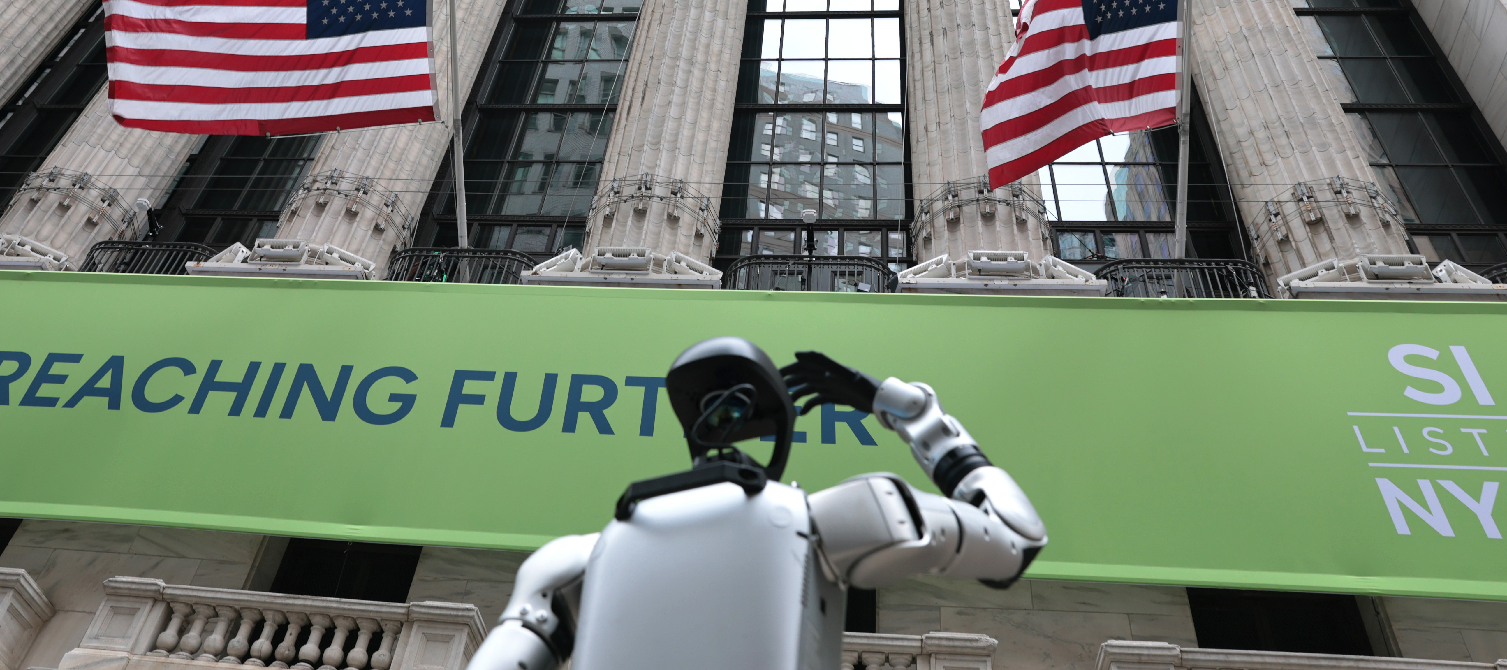 A Robostore robot does tricks for passersby in front of The New York Stock Exchange in 2025.