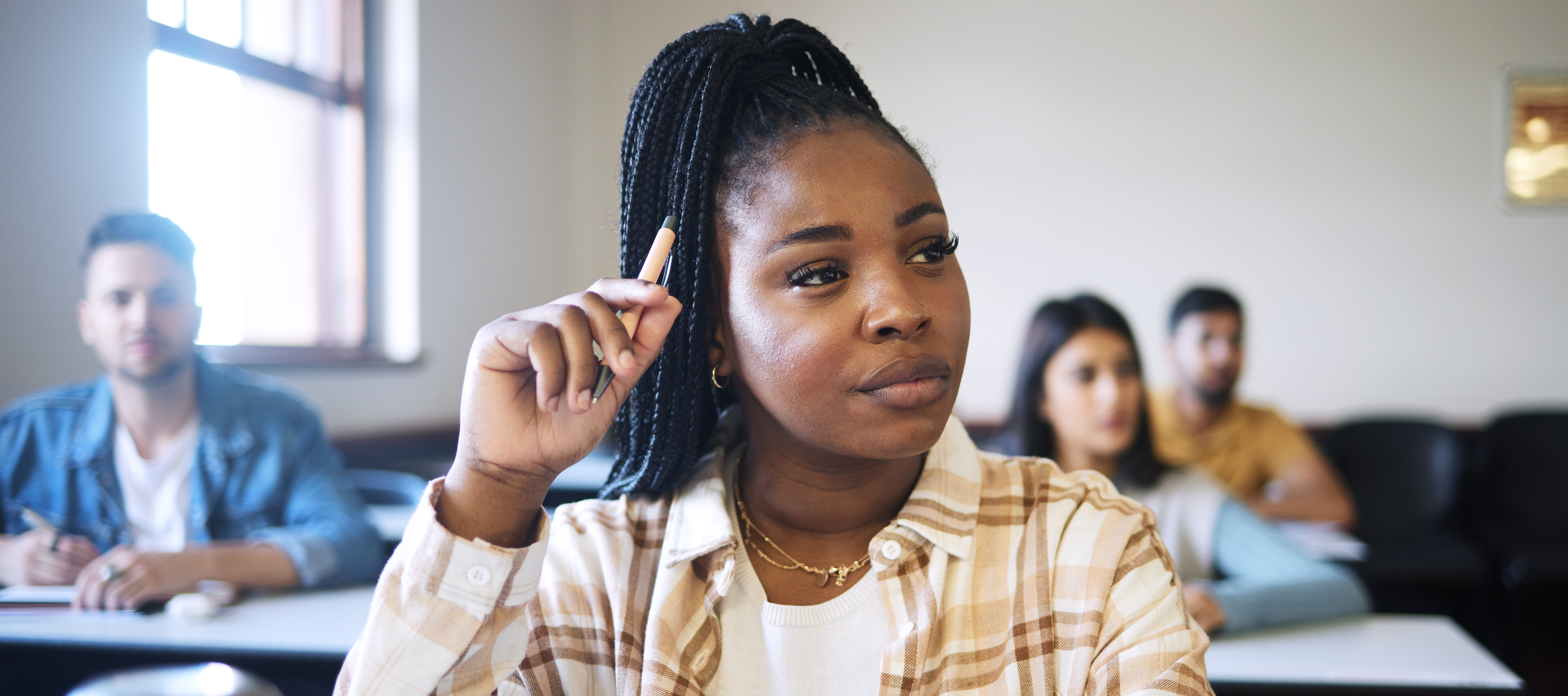 A young woman sits in a college class with an inquisitive look on her face.