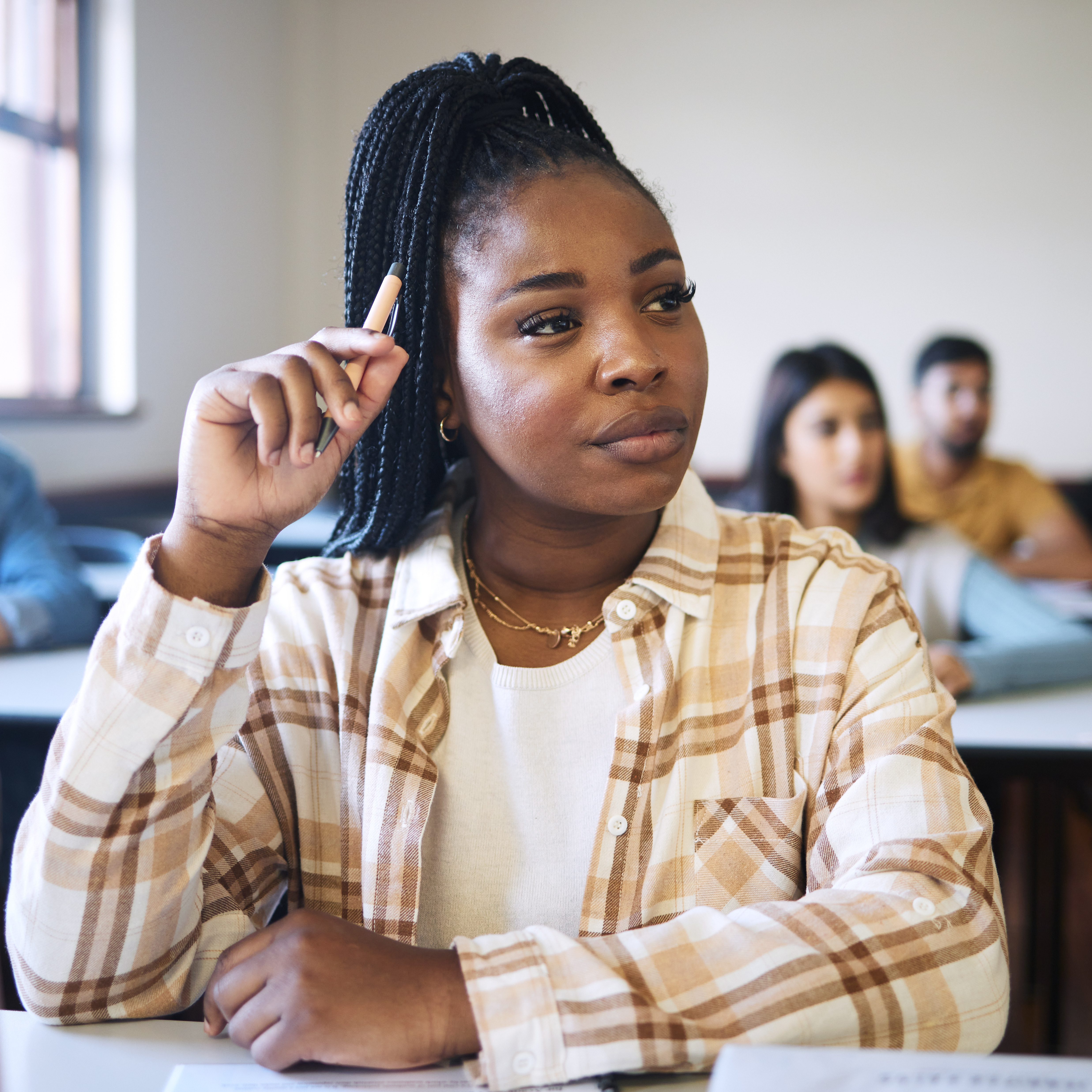 A young woman sits in a college class with an inquisitive look on her face.
