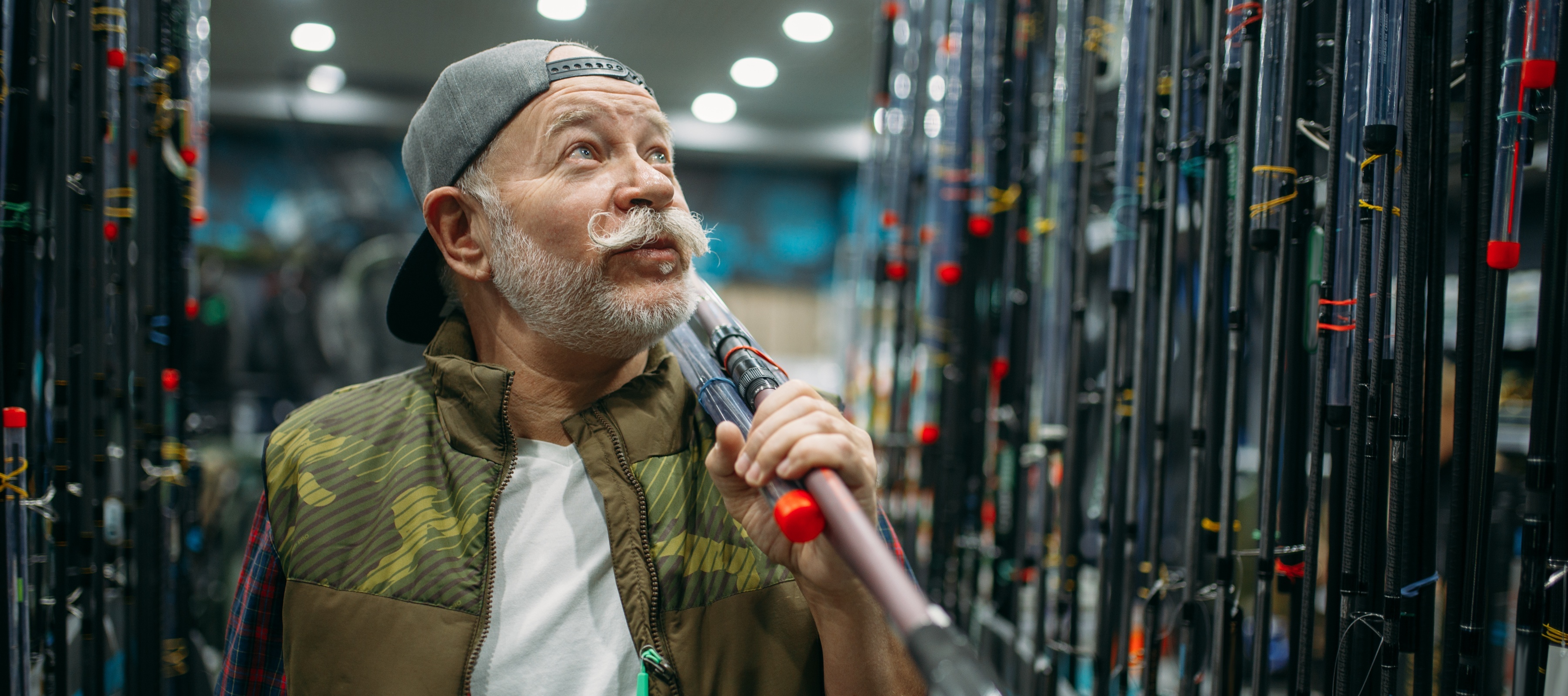 Man holding a fishing rod, looking up with surprise in the aisle.