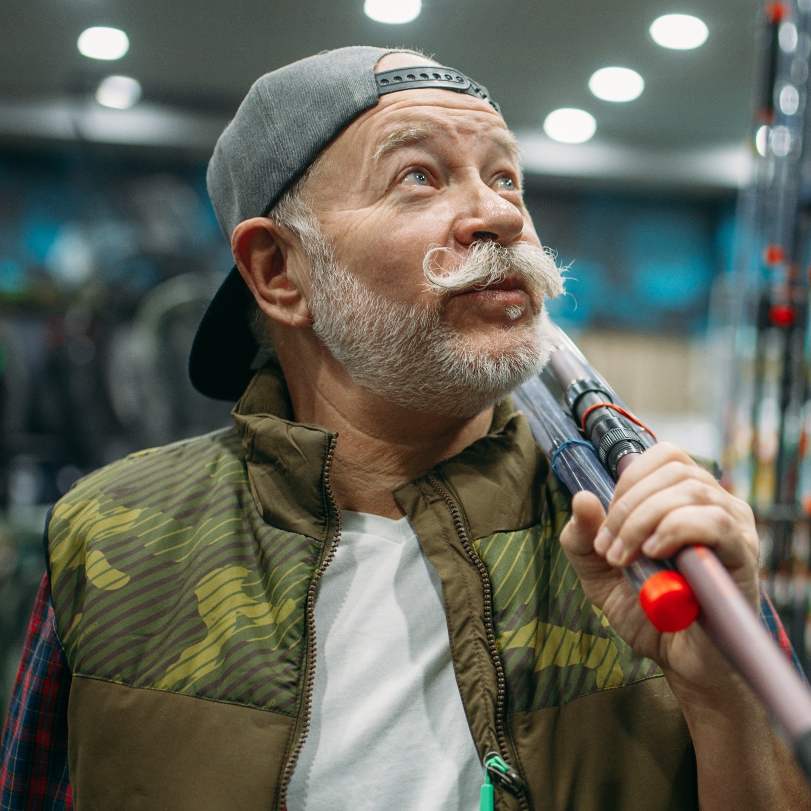 Man holding a fishing rod, looking up with surprise in the aisle.
