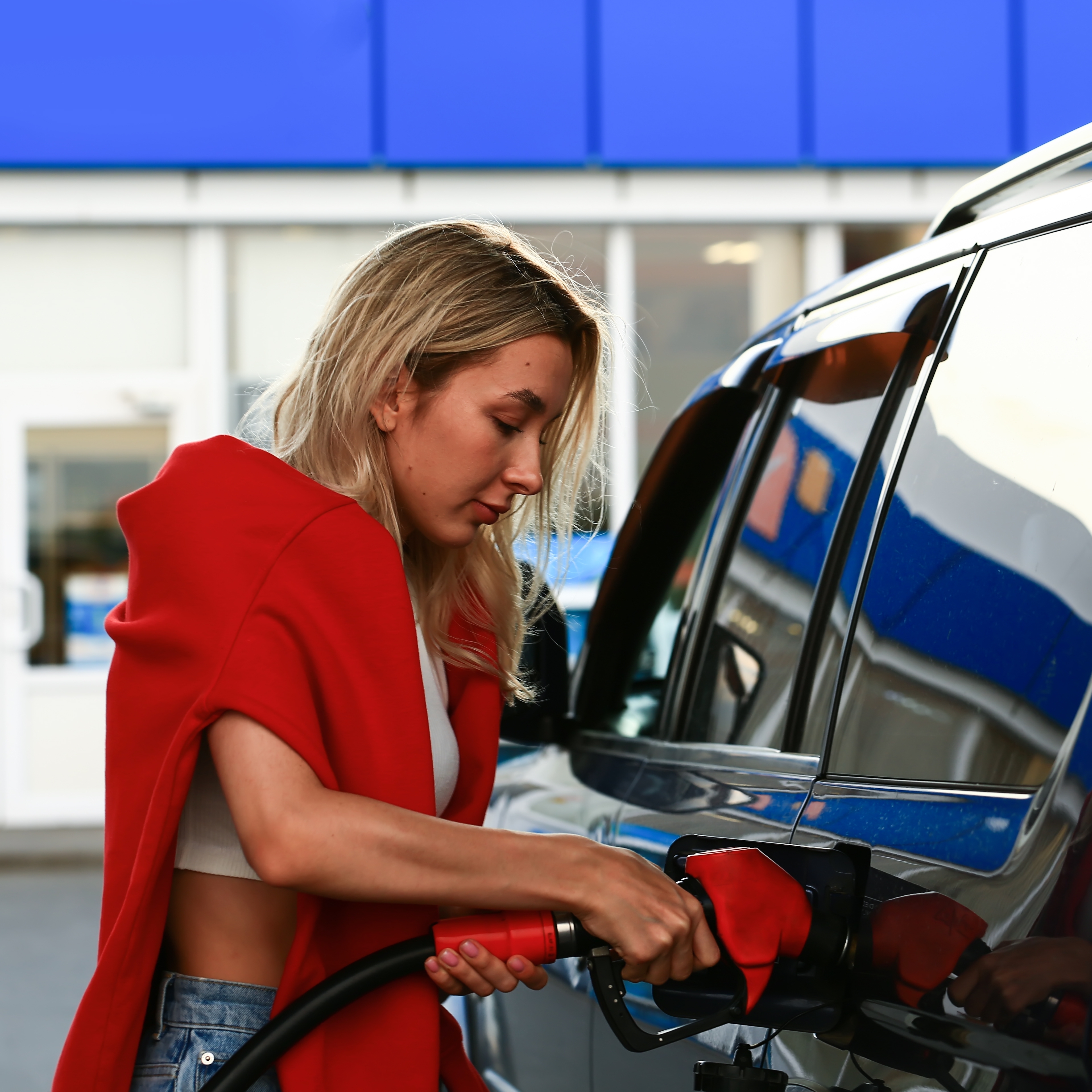 Young woman filling car with gas