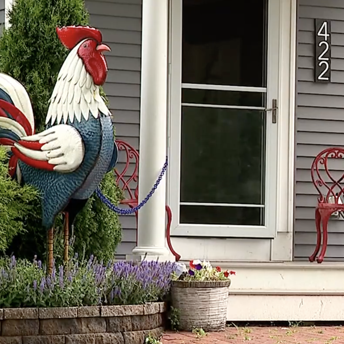 A photo of two rooster statues outside of a house