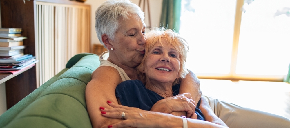 A photo of an older couple hugging on the couch