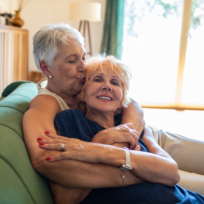 A photo of an older couple hugging on the couch