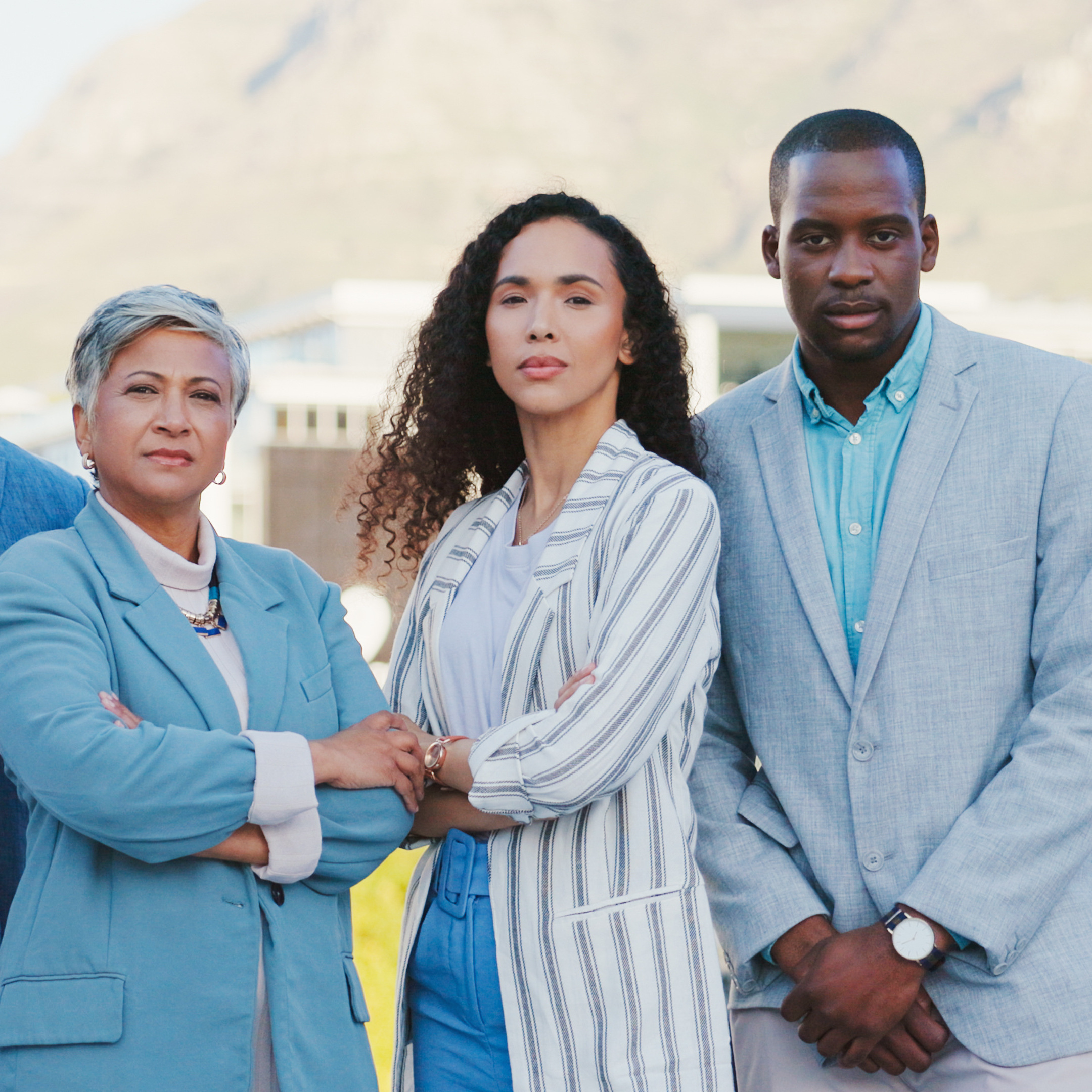 A diverse group of business people stand side by side facing the camera, looking insightful.