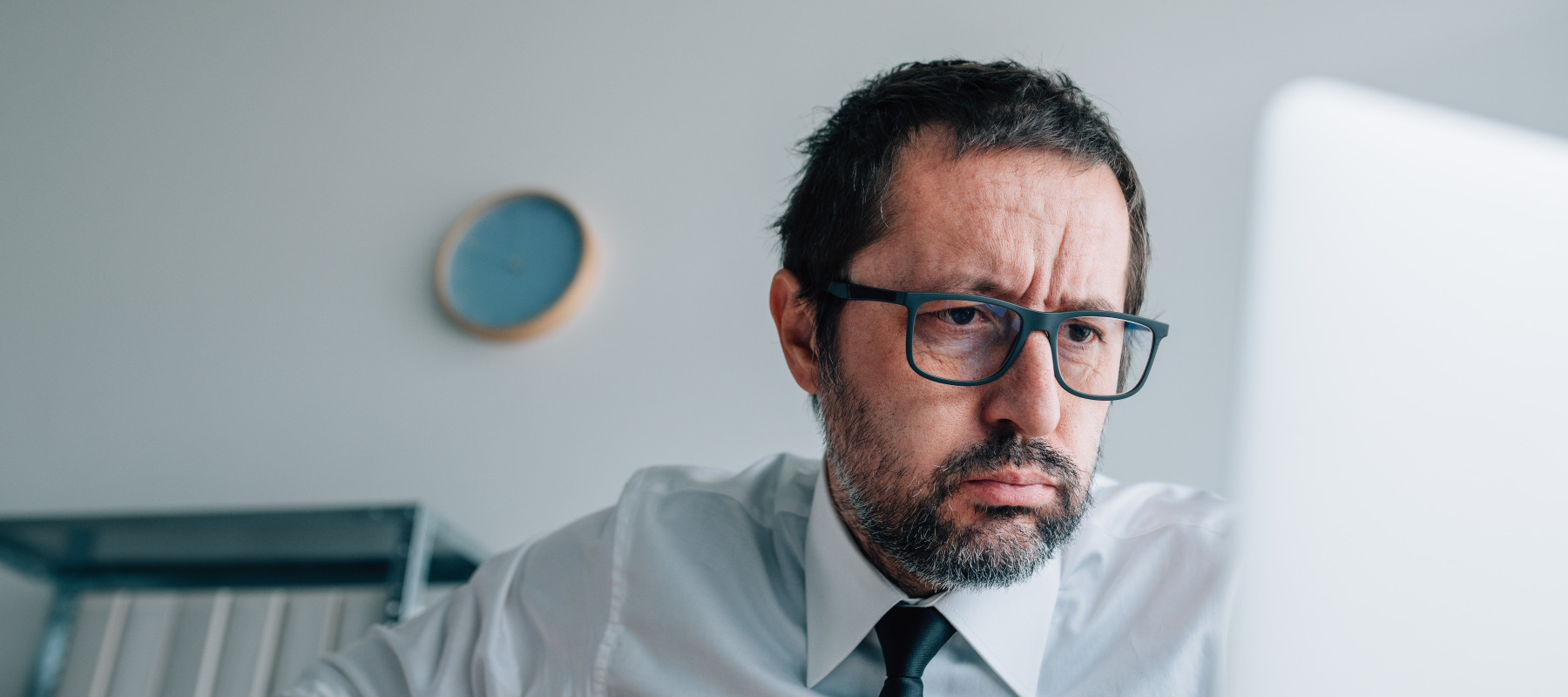 Man looks defeated, tired while looking at a computer screen.