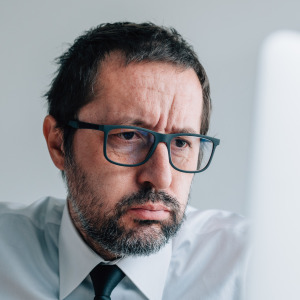 Man looks defeated, tired while looking at a computer screen.