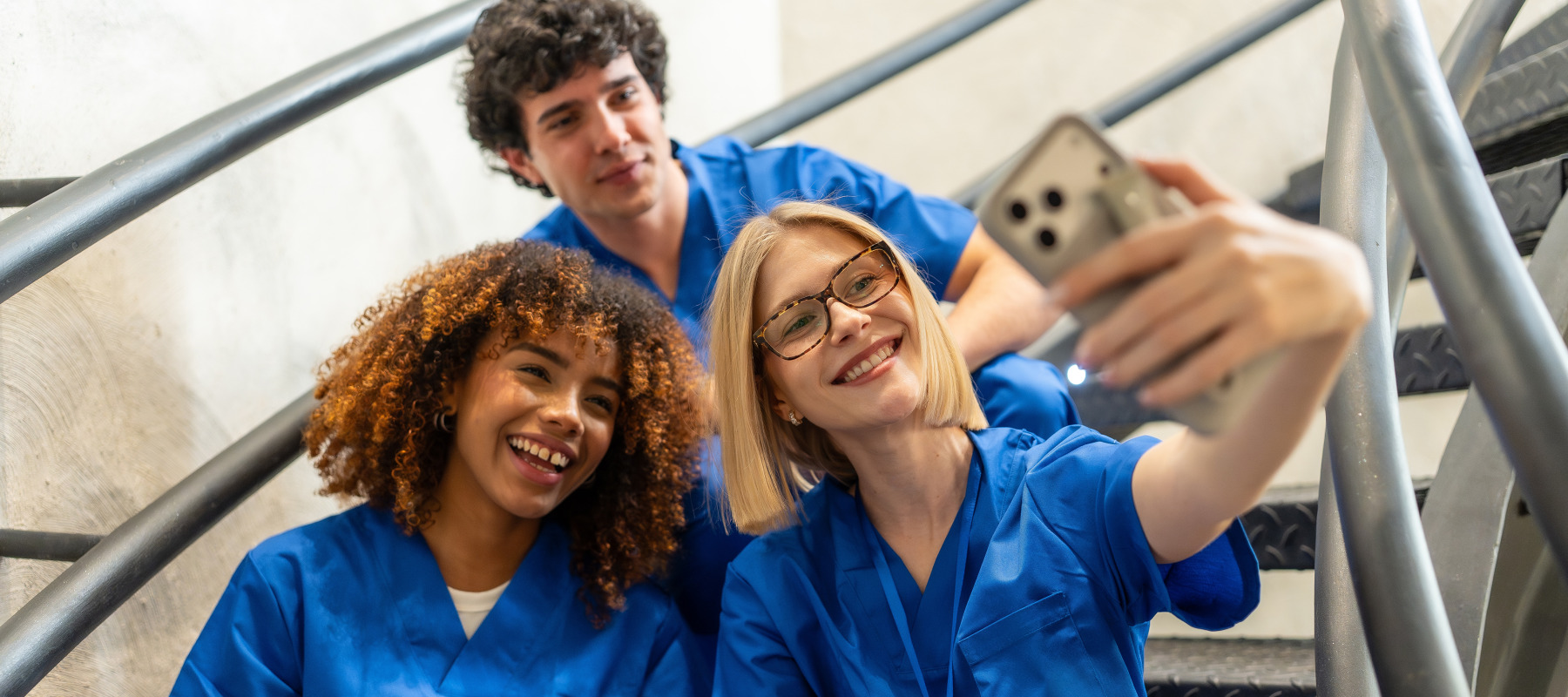 A group of nurses take a selfie on stairs.