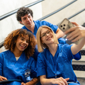 A group of nurses take a selfie on stairs.