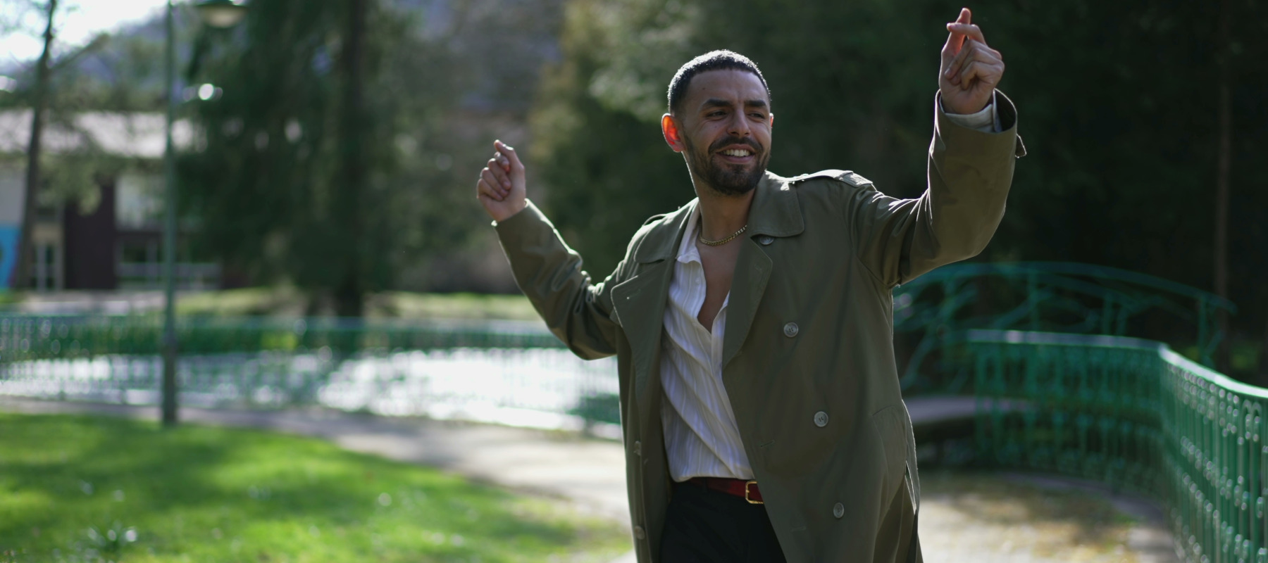 A man dances while ambling about on a park pathway.