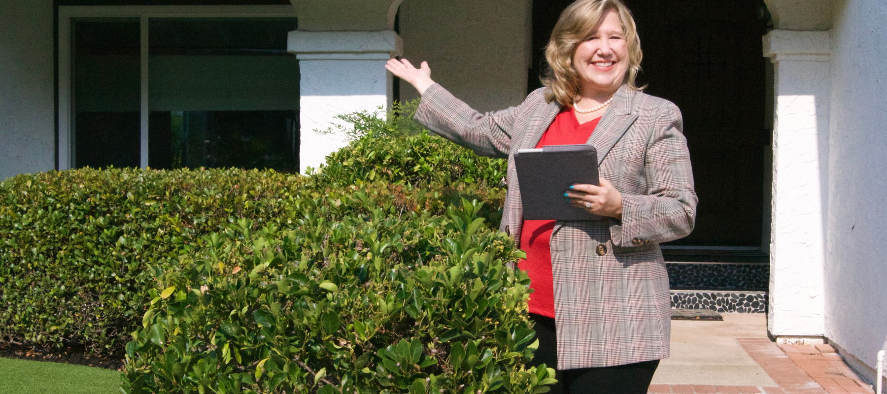 Real estate agent posing in front of house