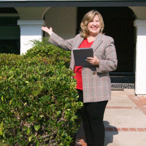 Real estate agent posing in front of house