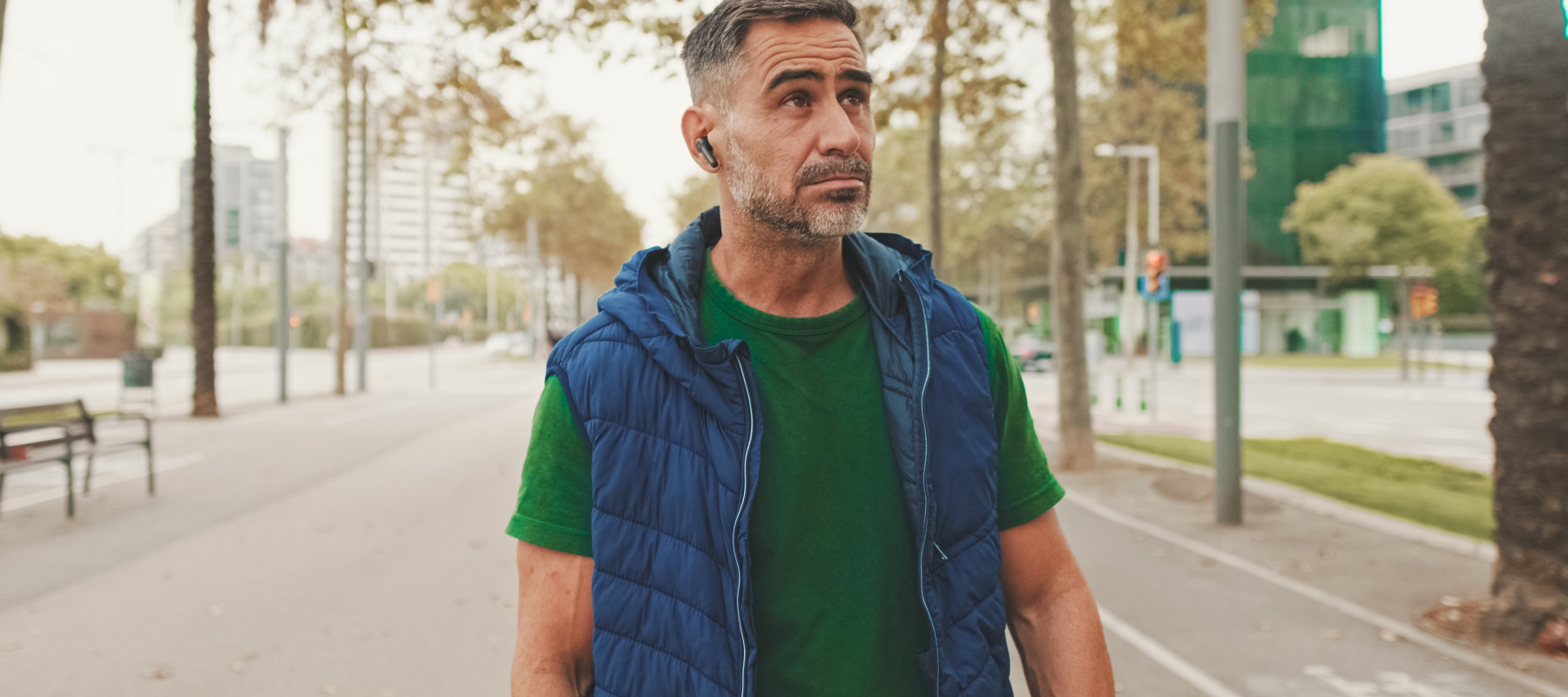 Pensive man walking with earpiece in