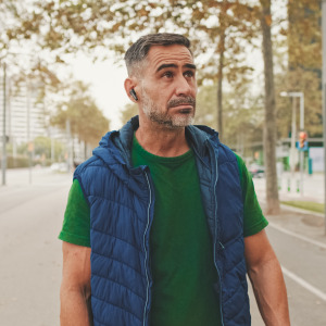 Pensive man walking with earpiece in