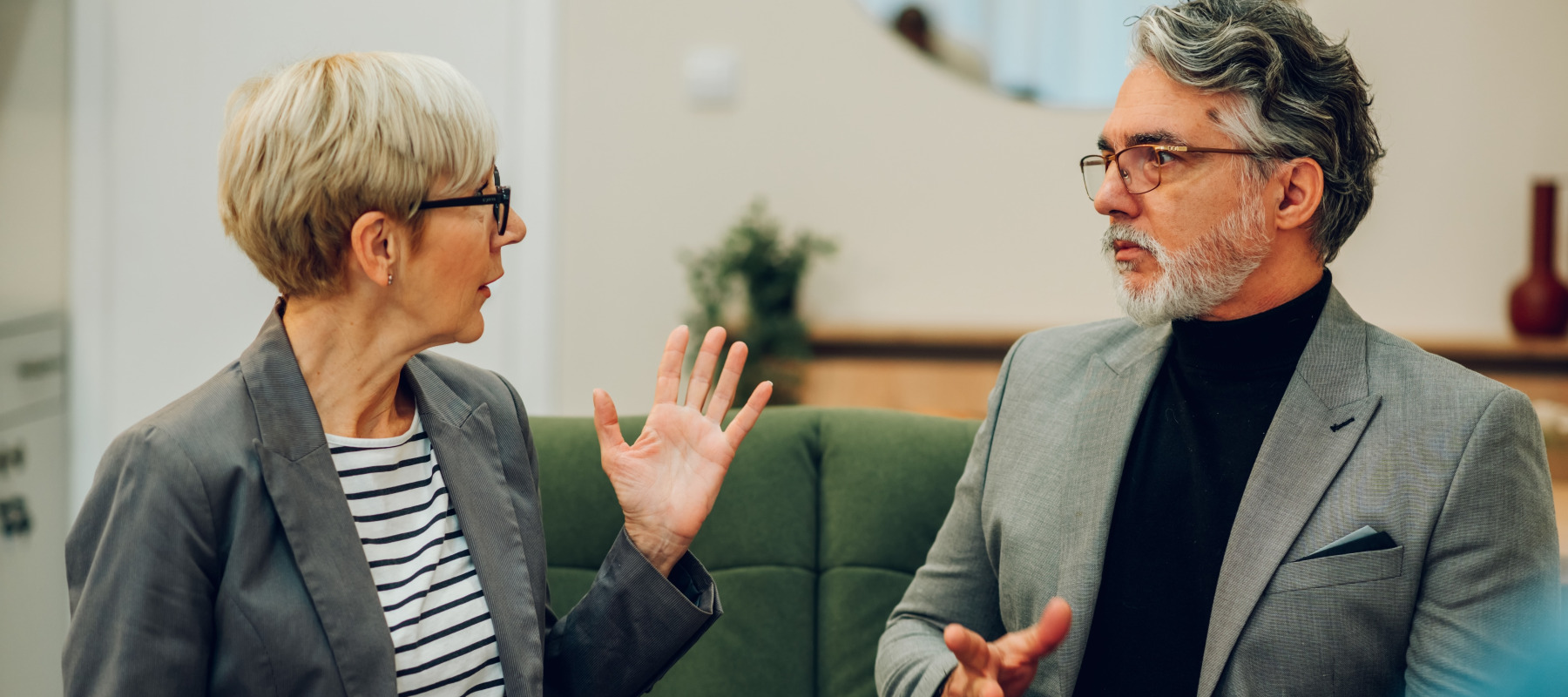Older divorced couple argue in a room.