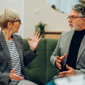 Older divorced couple argue in a room.