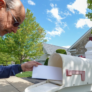 An older man checks his mailbox.