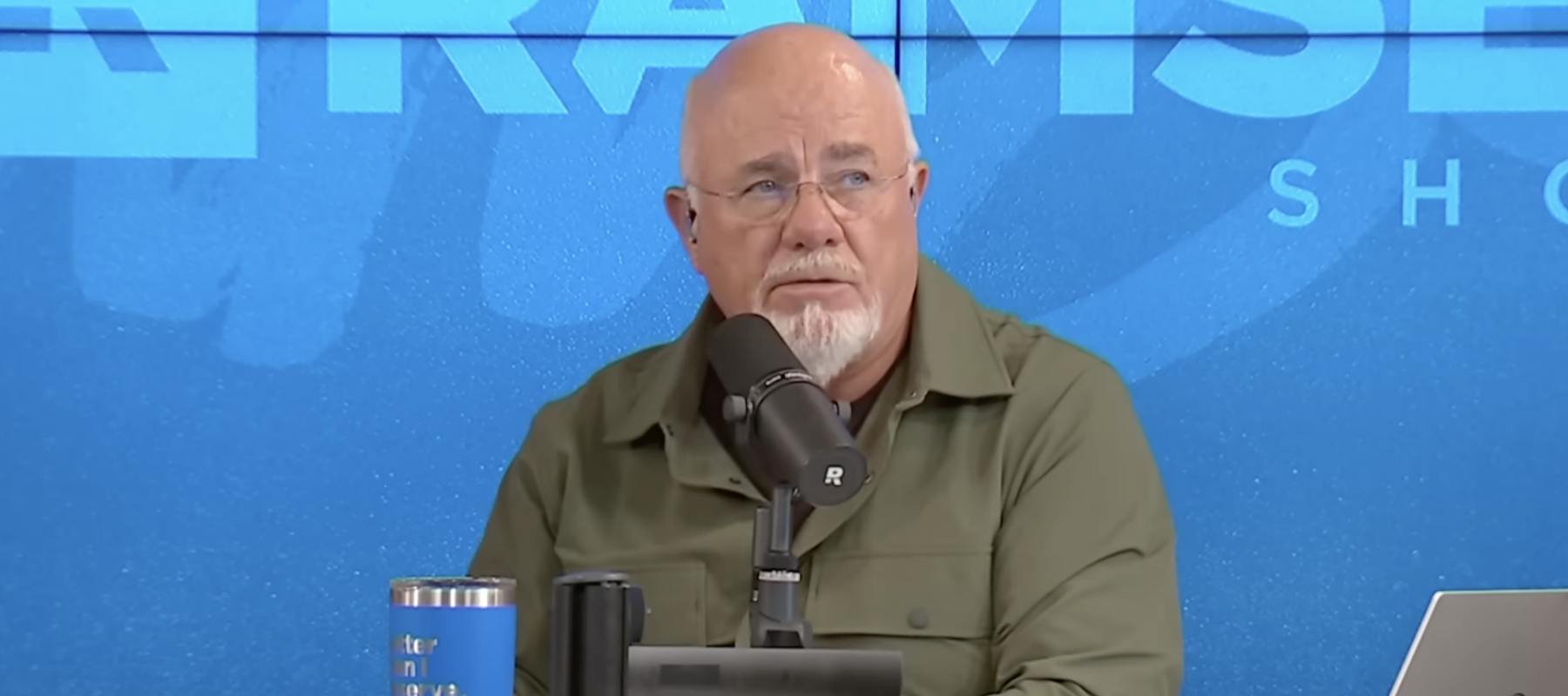 Dave Ramsey is seen behind the desk on his show The Ramsey Show giving advice about car insurance deductibles.