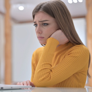 A concerned woman looking at her computer.