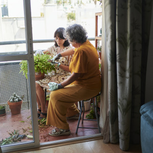 A middle-aged woman helps her aging mother with gardening.