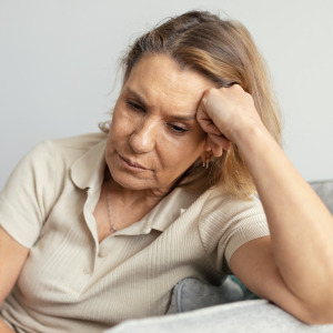 Contemplative couple sits on couch, looking unhappy.