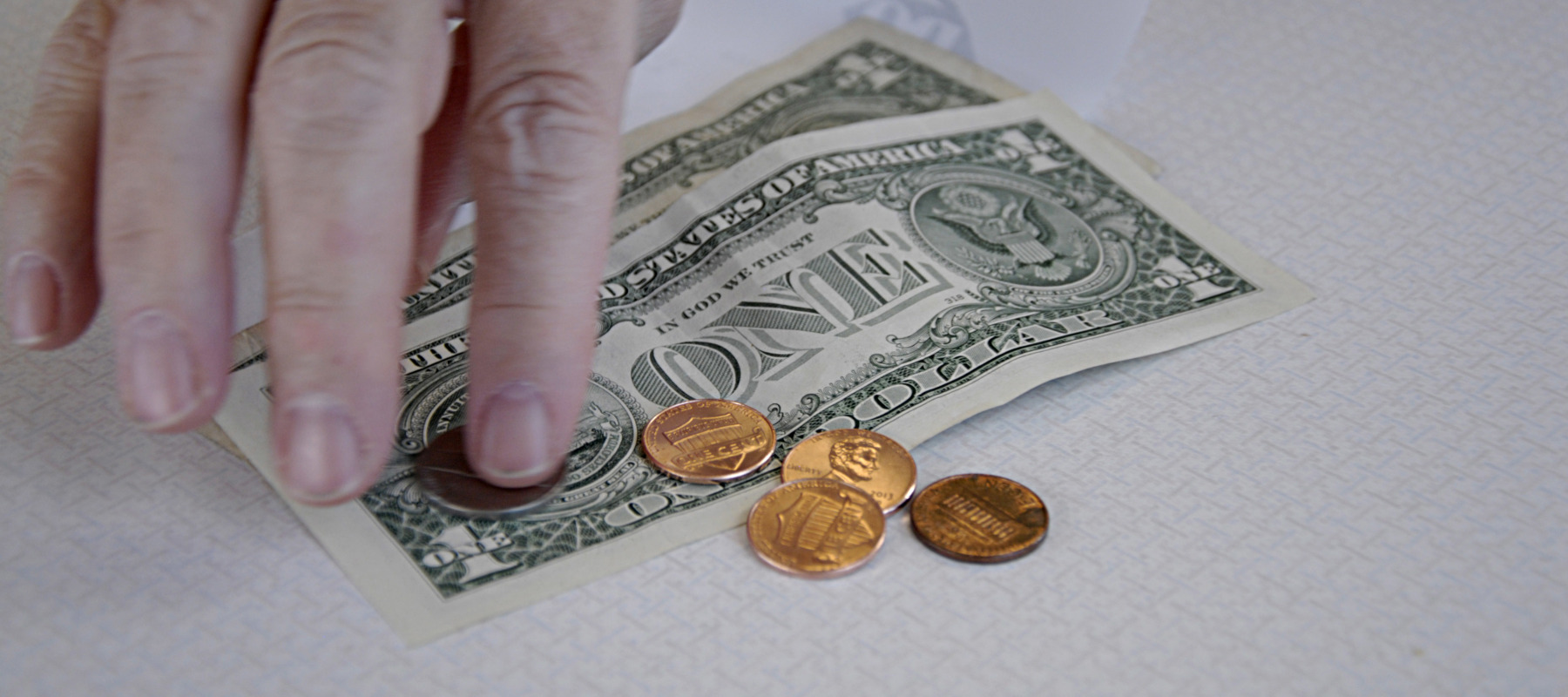 A customer pays for a purchase using cash and pennies.