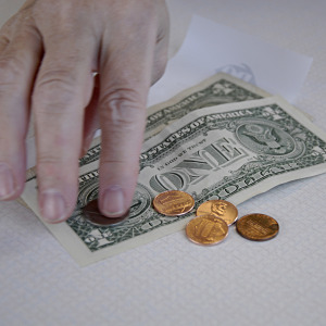 A customer pays for a purchase using cash and pennies.