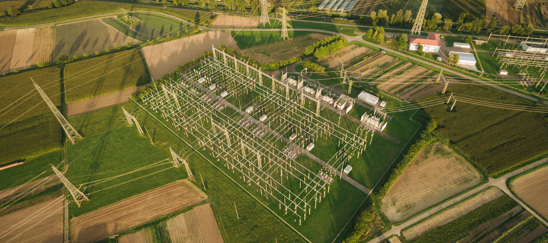 An aerial view showcases an electrical substation nestled in a rural, farmland area.