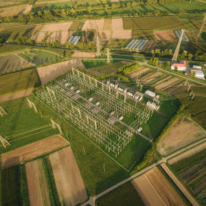 An aerial view showcases an electrical substation nestled in a rural, farmland area.