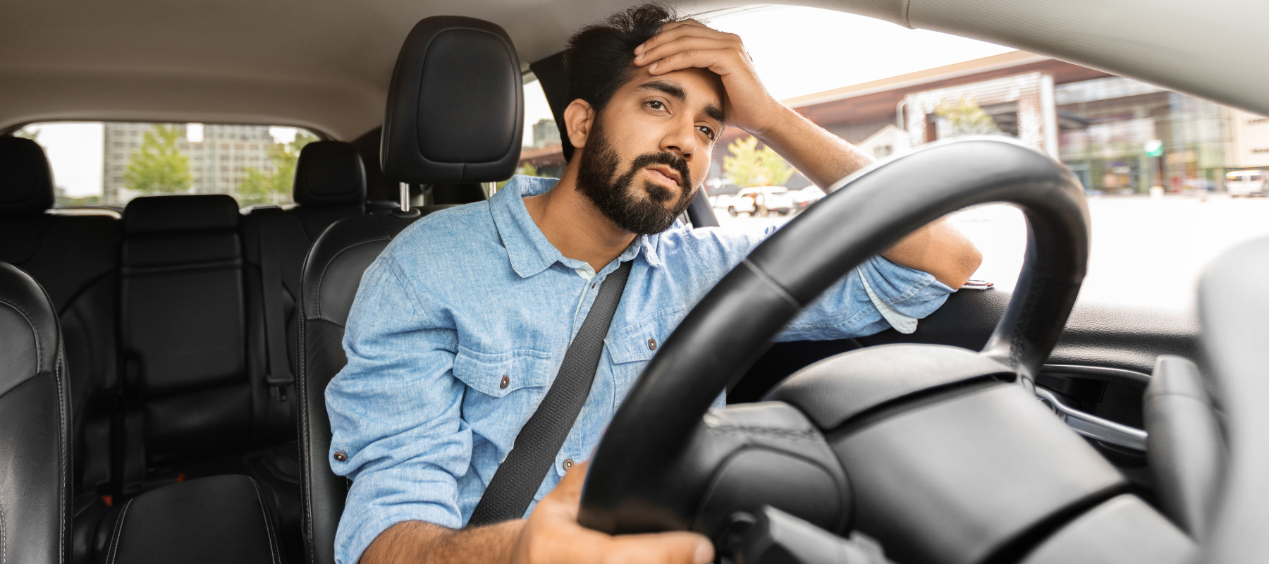 A frustrated driver puts his hand on his head.