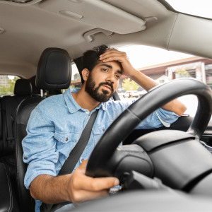 A frustrated driver puts his hand on his head.