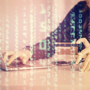 A woman works on a laptop with her credit card in hand while binary code is overlayed on top.