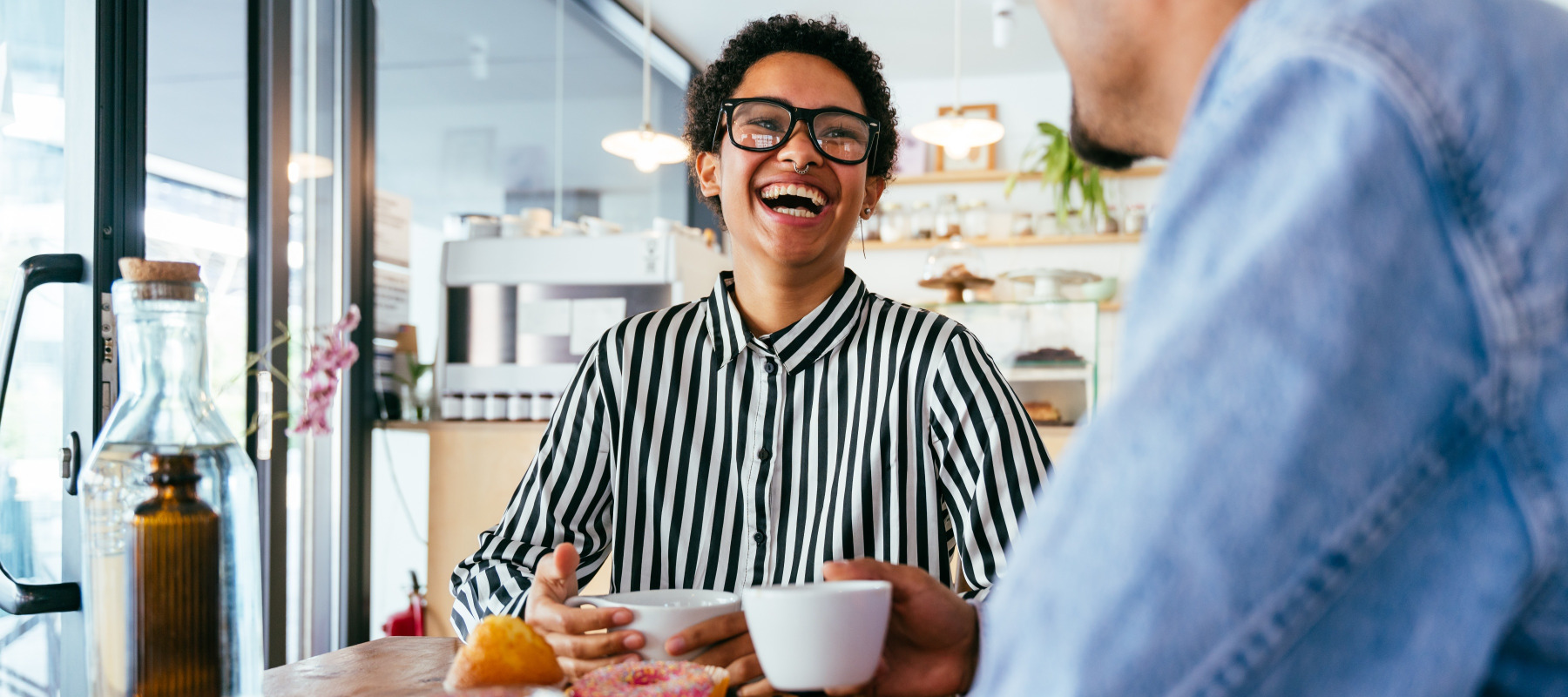 Young couple sit in a cafeteria, chatting and laughing.
