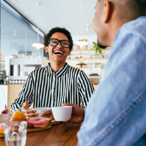 Young workers seen in cafeteria, laughing and drinking coffee.