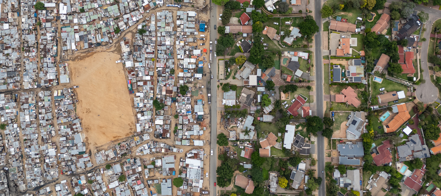 An aerial view of lower-income housing, spaced closely together, alongside wealthier homes with plenty of living space.
