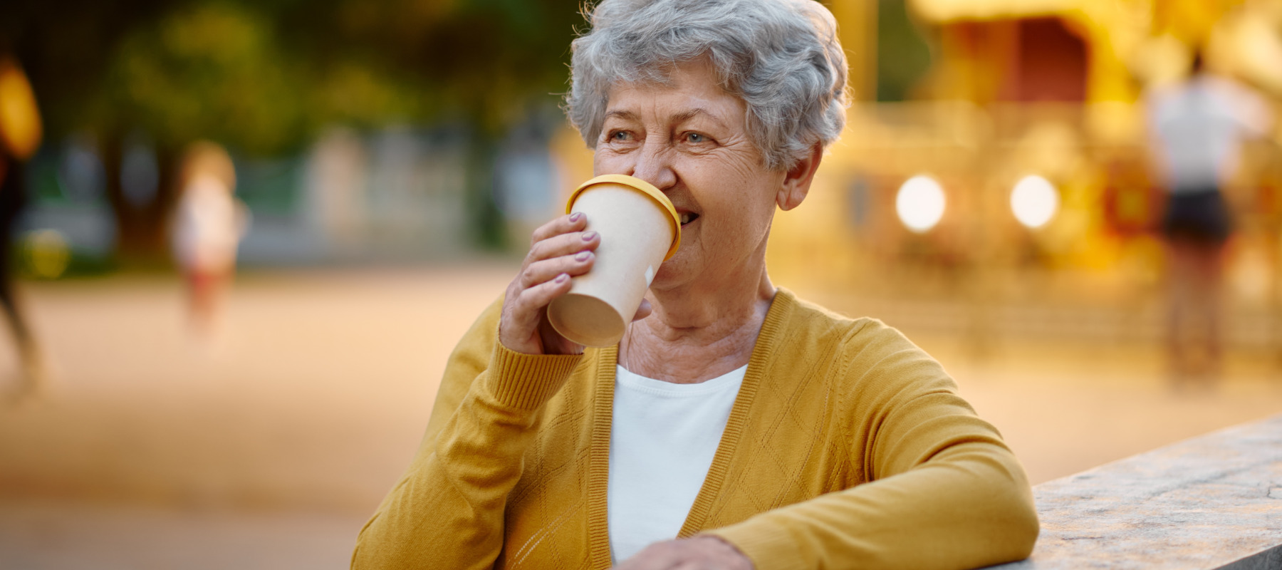 Elderly woman drinking a takeout coffee